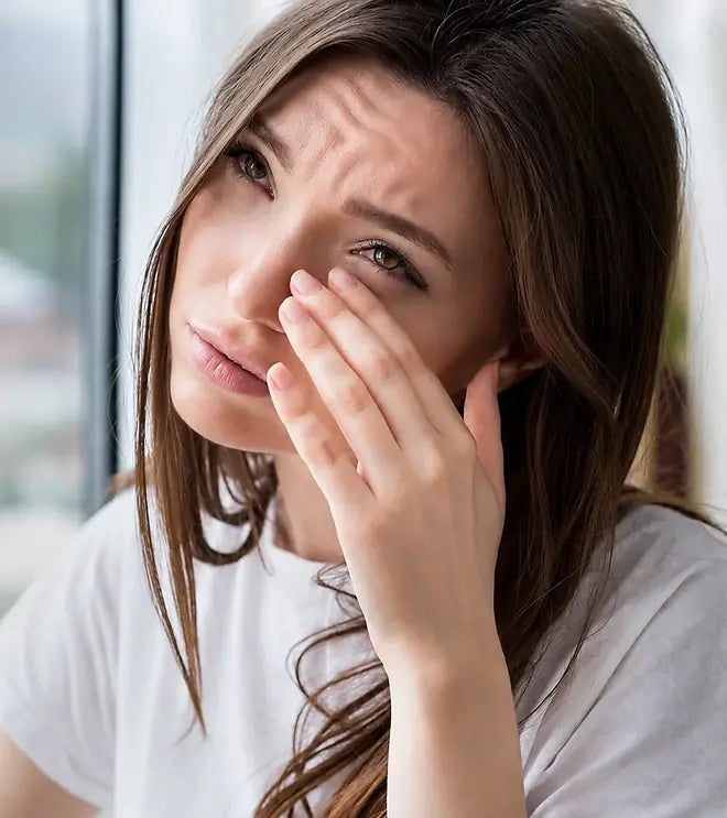 A woman rubbing her tired, dry eye